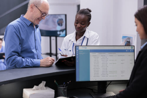 A female doctor helps a male fill paperwork out